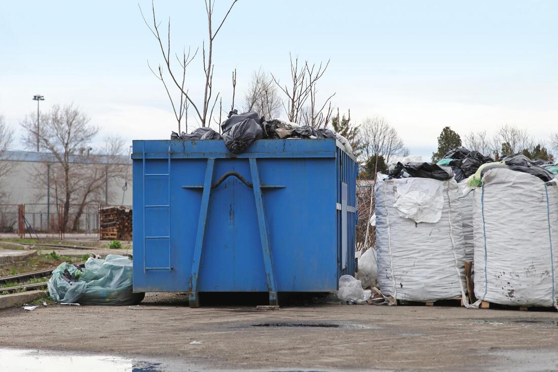 a dump space with blue huge trash container